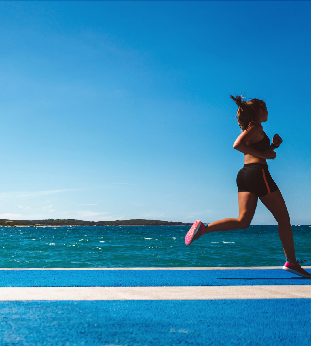 woman in pink sneakers running along ocean