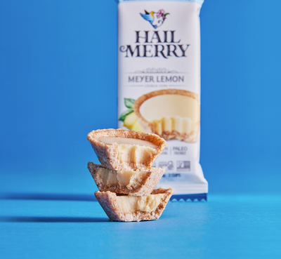 Stack of three Hail Merry Raw Meyer Lemon cups outside of package. Vegan. Organic. No added Sugar. Healthy Snack 